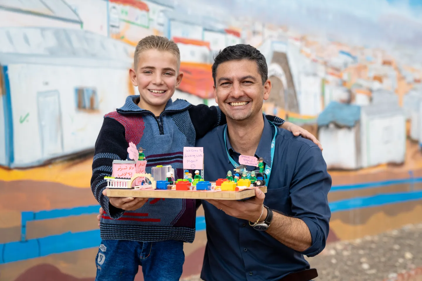 A boy and man hold a LEGO brick model 