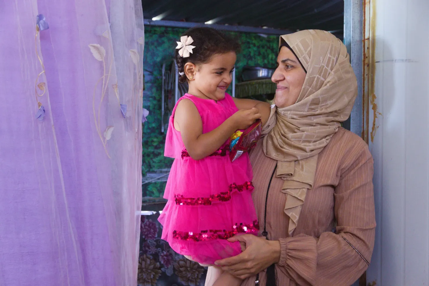 A Mother holding her daughter as they smile at each other