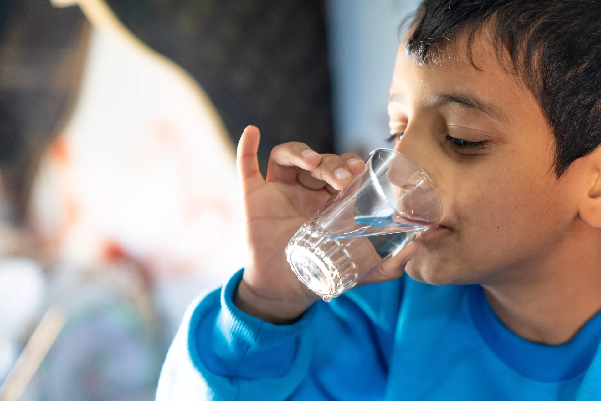 A boy drinks a glass of water