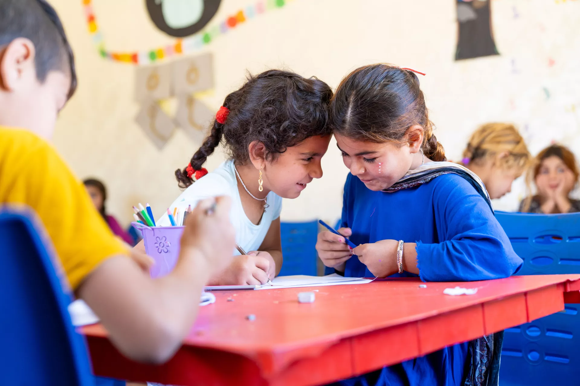 Two girls sit together at a classroom table