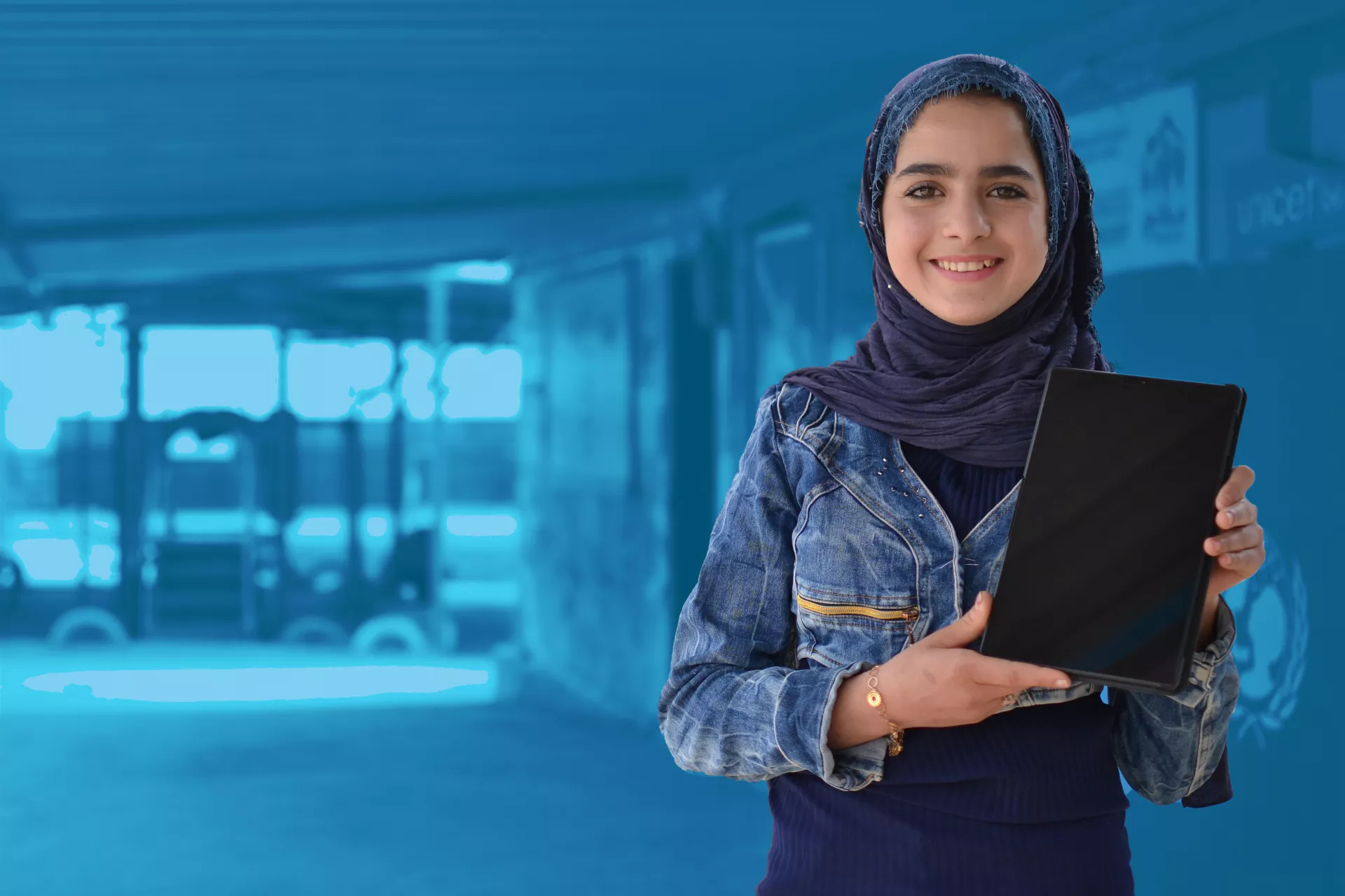 Girl smiles at the camera while holding her tablet