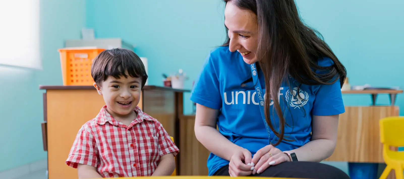 A UNICEF employee and a child laughing.