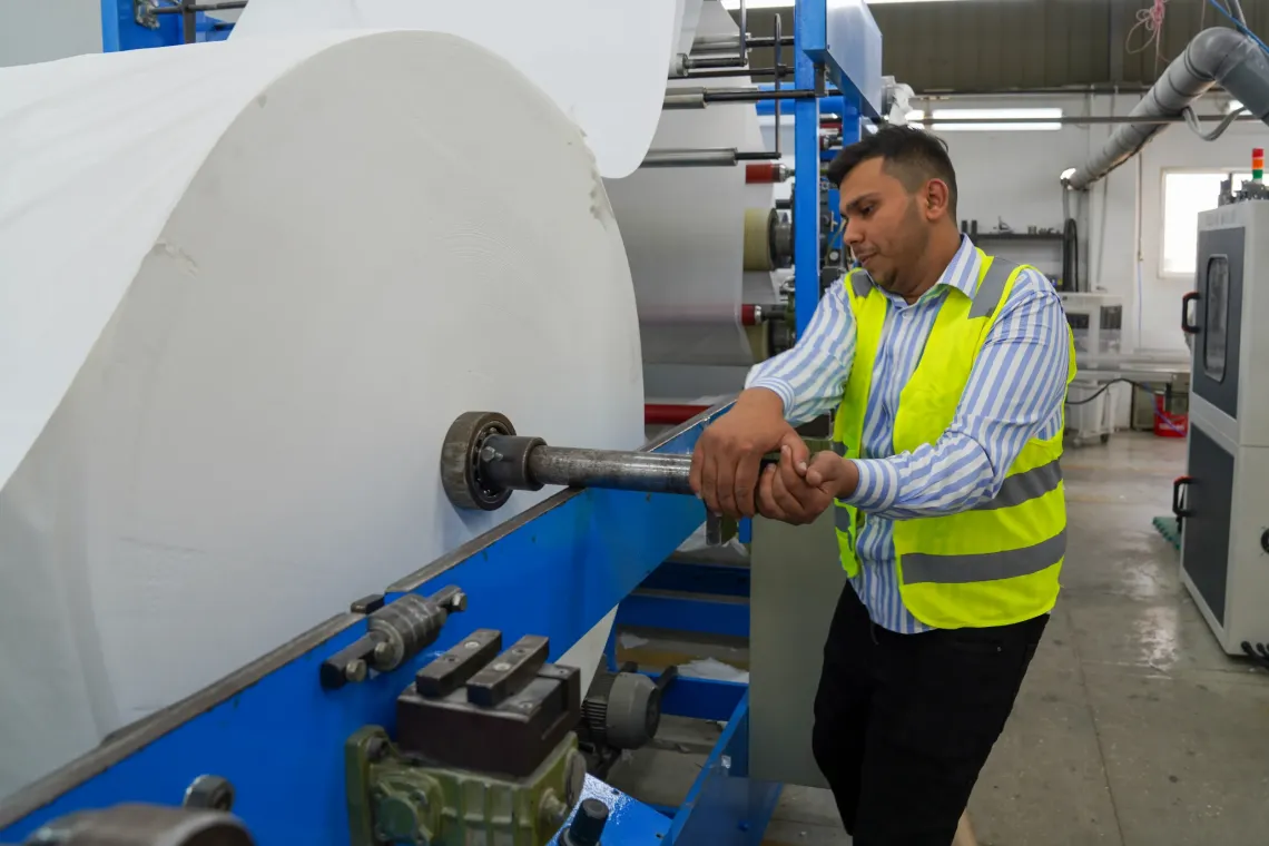 Mohammad, 19, at work, loading a paper roll