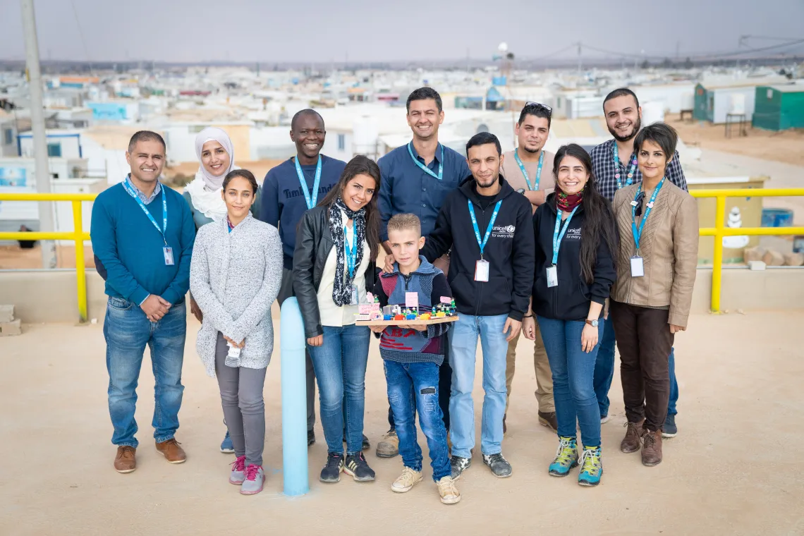 A boy poses with a team of people