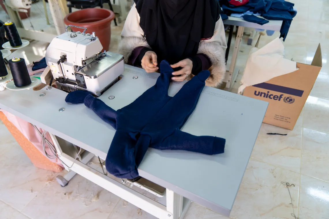A woman tailoring a baby jumpsuit