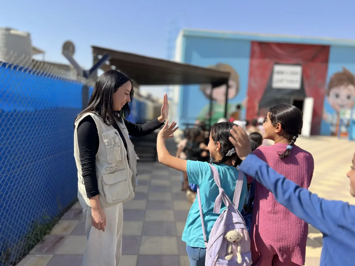 Jana interacts with the children through high-fives, promoting a positive and welcoming environment.