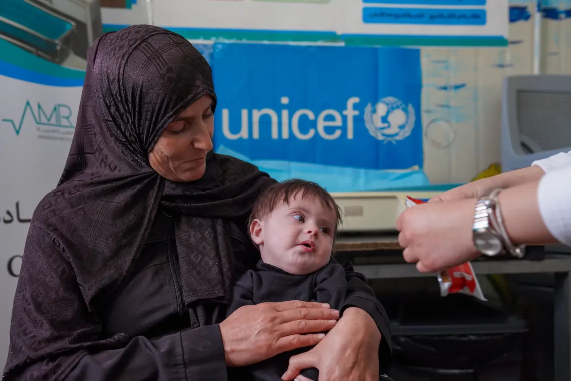 Hasan being presented with Ready-to-Use Therapeutic Food (RUTF) by the health worker at the Nutrition clinic