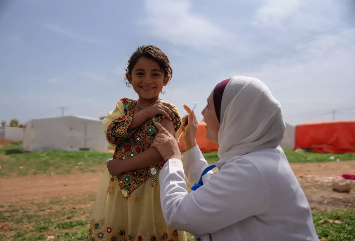A healthcare worker vaccinating a girl child.