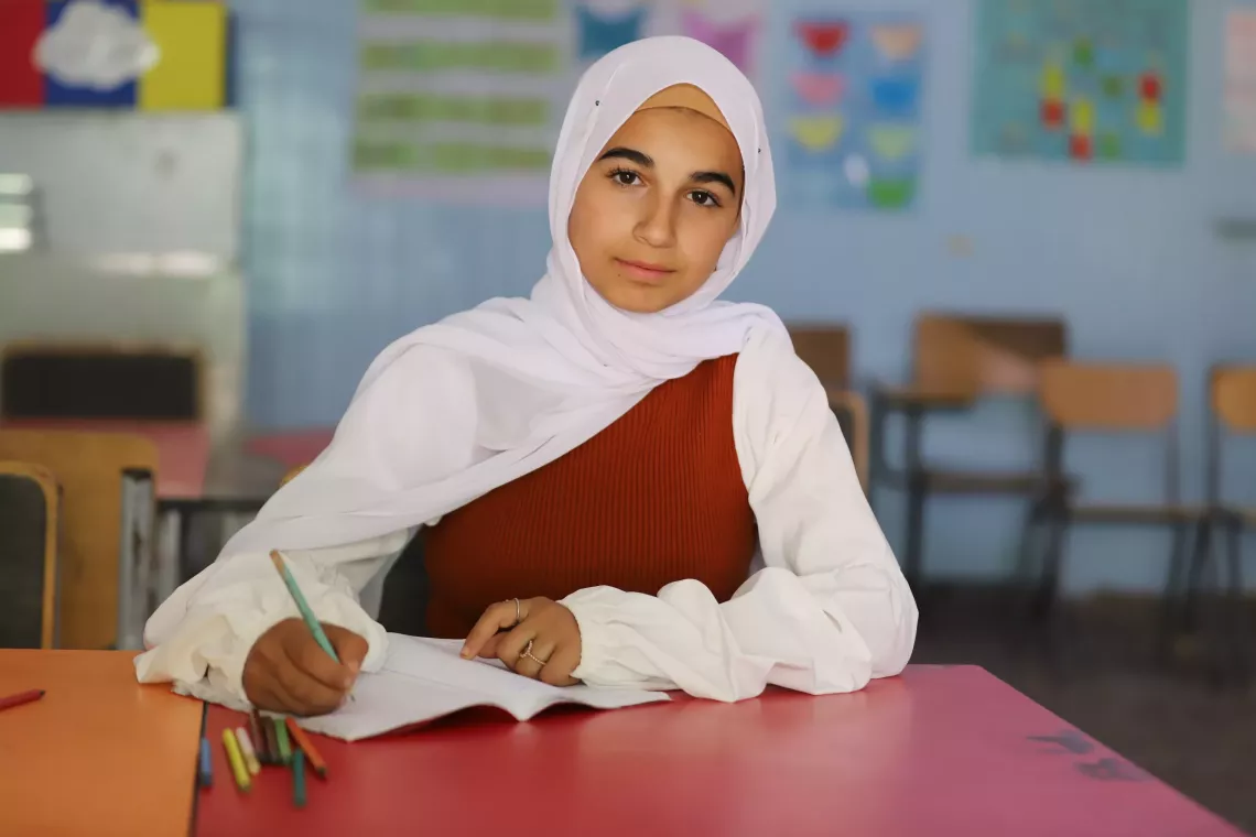 A girl sits on her desk, writing.