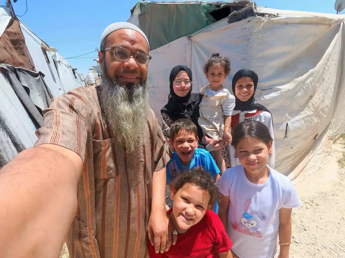 Abu Sham taking a selfie with his children in front of their shelter in Garden camp/ Jordan