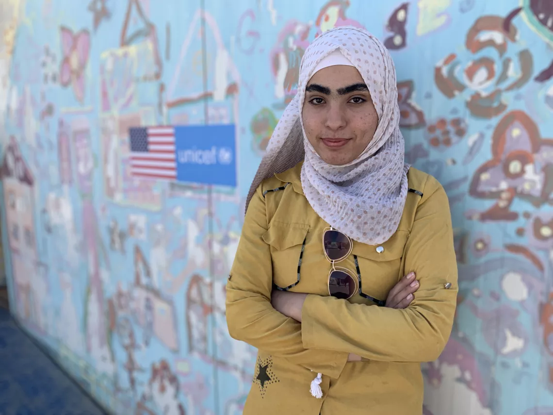 A girl looking at camera with US flag and UNICEF logo in the background