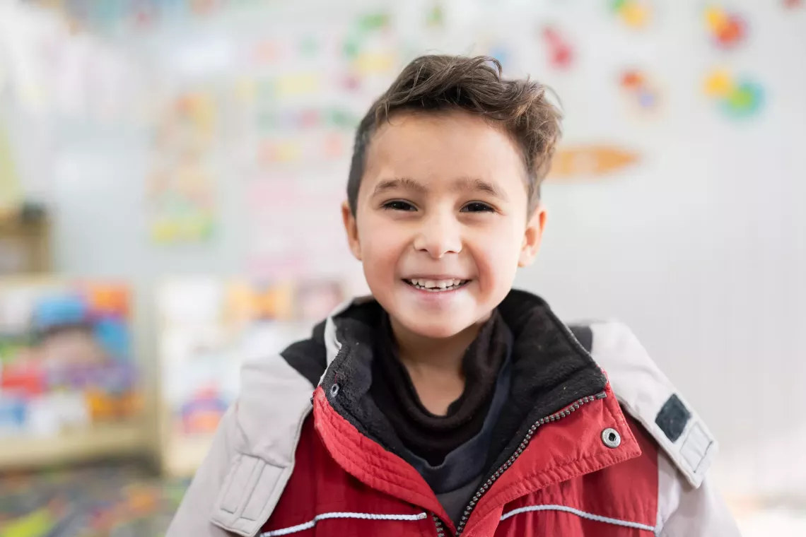 A little boy smiling to the camera.