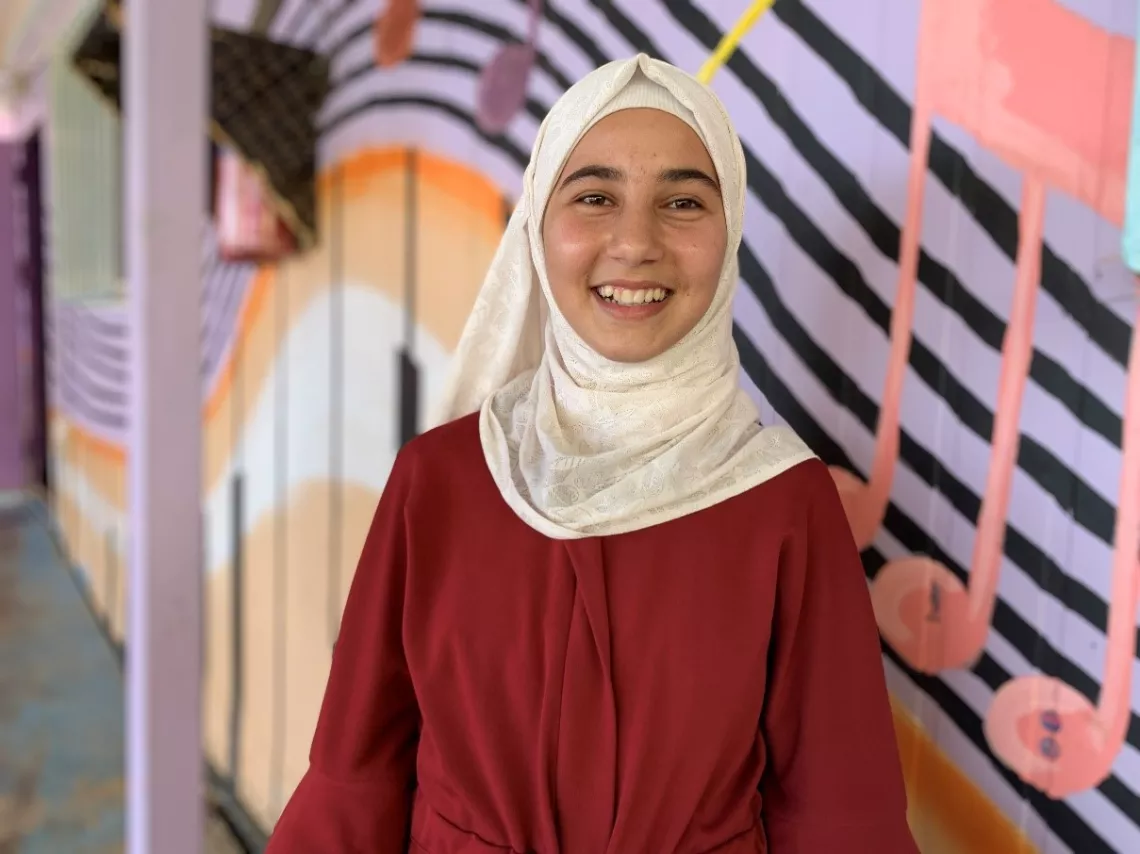 Sara, 13, poses outside the music room at a Makani centre in Azraq Refugee Camp in Jordan.