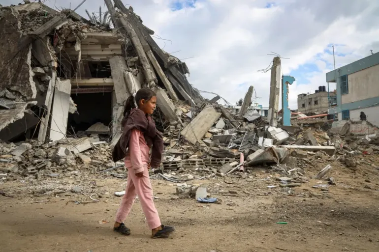 A girl child walks through a heavily damaged area in Gaza Strip