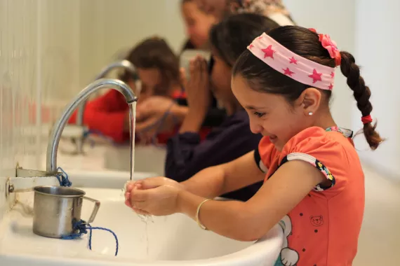 A girl washes her hands at a sink