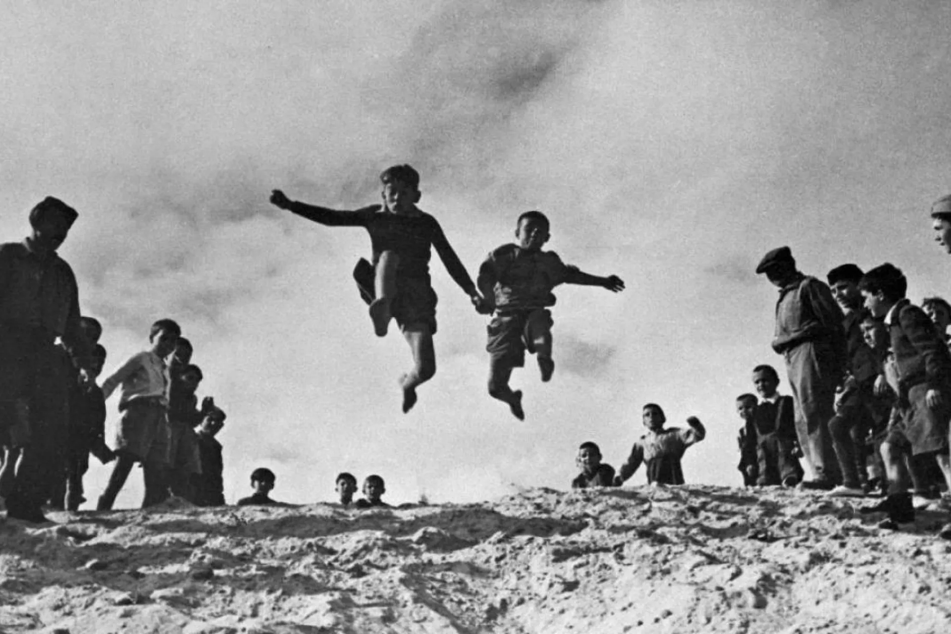 old photo of two kids jumping somewhere and holding hands