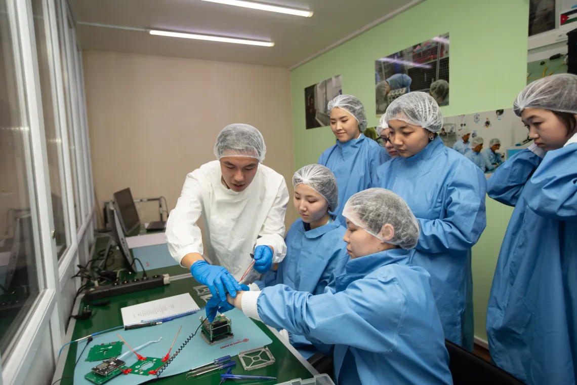 UniSat бағдарламасының қатысушылары тәлімгердің жетекшілігімен наноспутник құрастырумен айналысып отыр.  Алматы, Қазақстан.