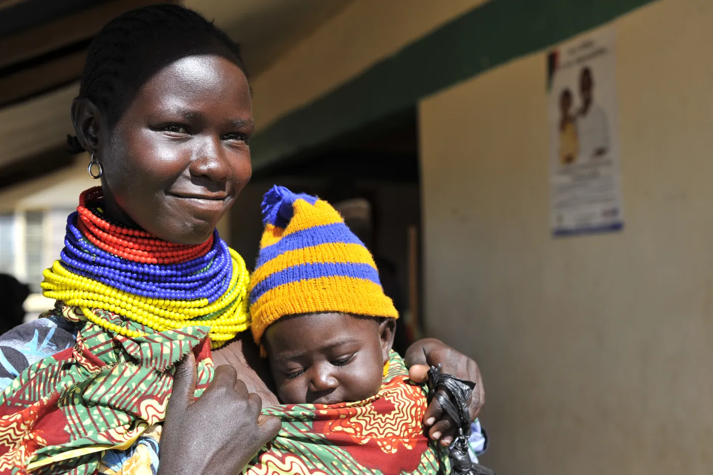 A mother carrying her baby and smiling.