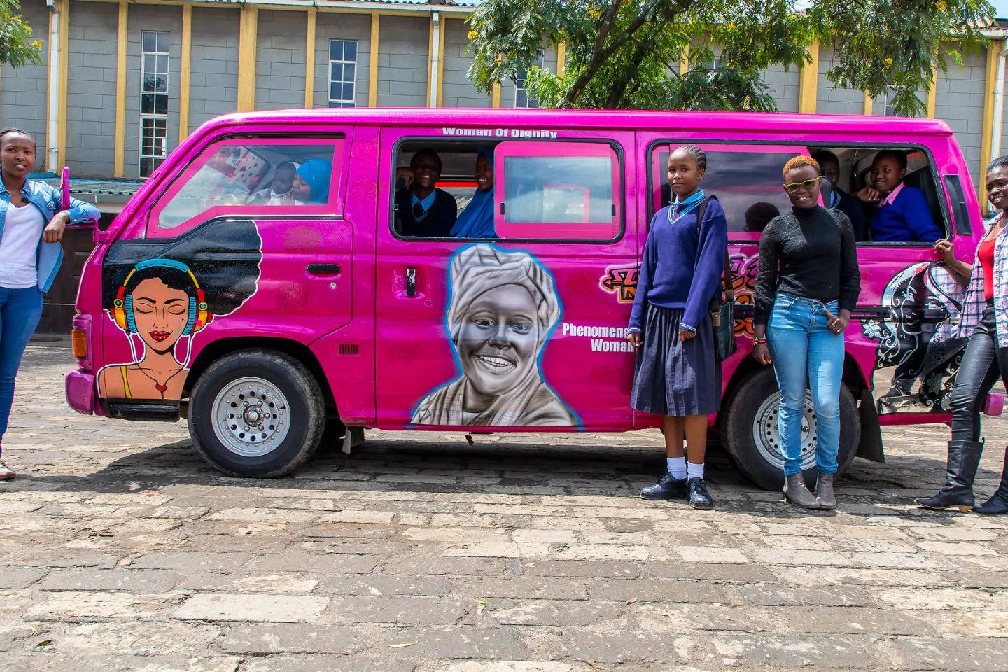 Girls stand next to a newly designed pubic van (matatu) created to celebrate women and girls.