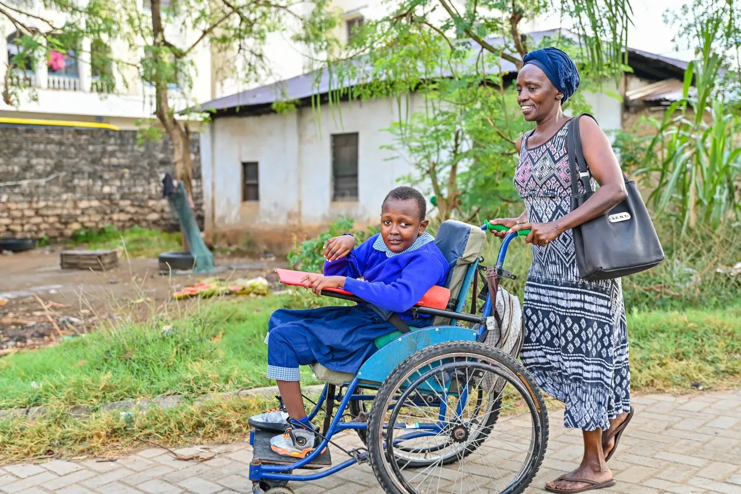 A mother and her child, who uses a wheelchair, walk to school in Mombasa.