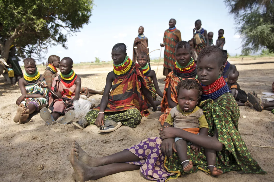A group of women from the Turkana community in Kenya sit with their children outdoors.