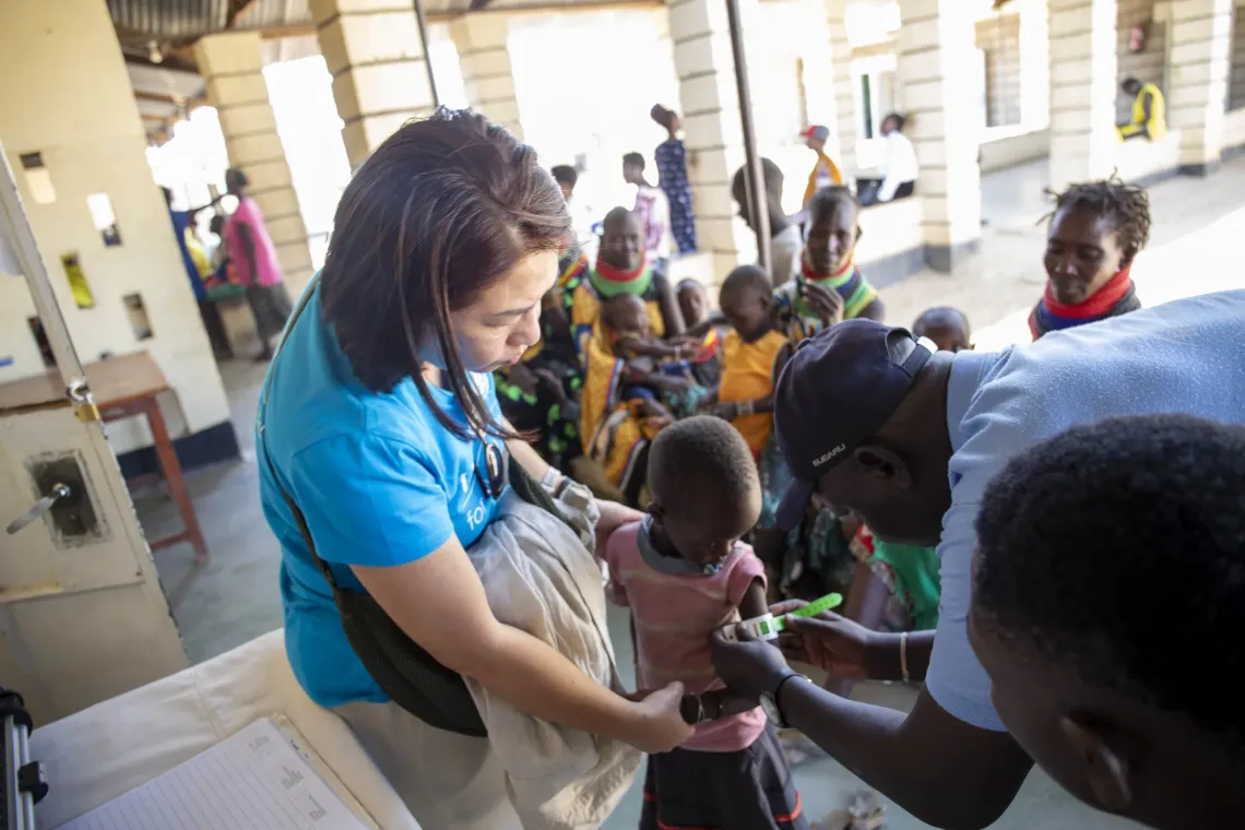 Melvin, 10, has her mid-upper arm circumference measured using a MUAC tape