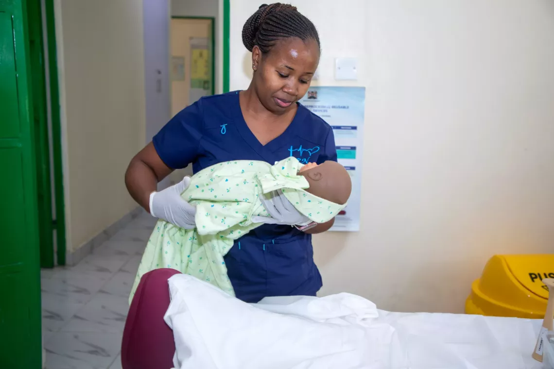Nurse Midwife Maureen Kaloki demonstrates using a baby model