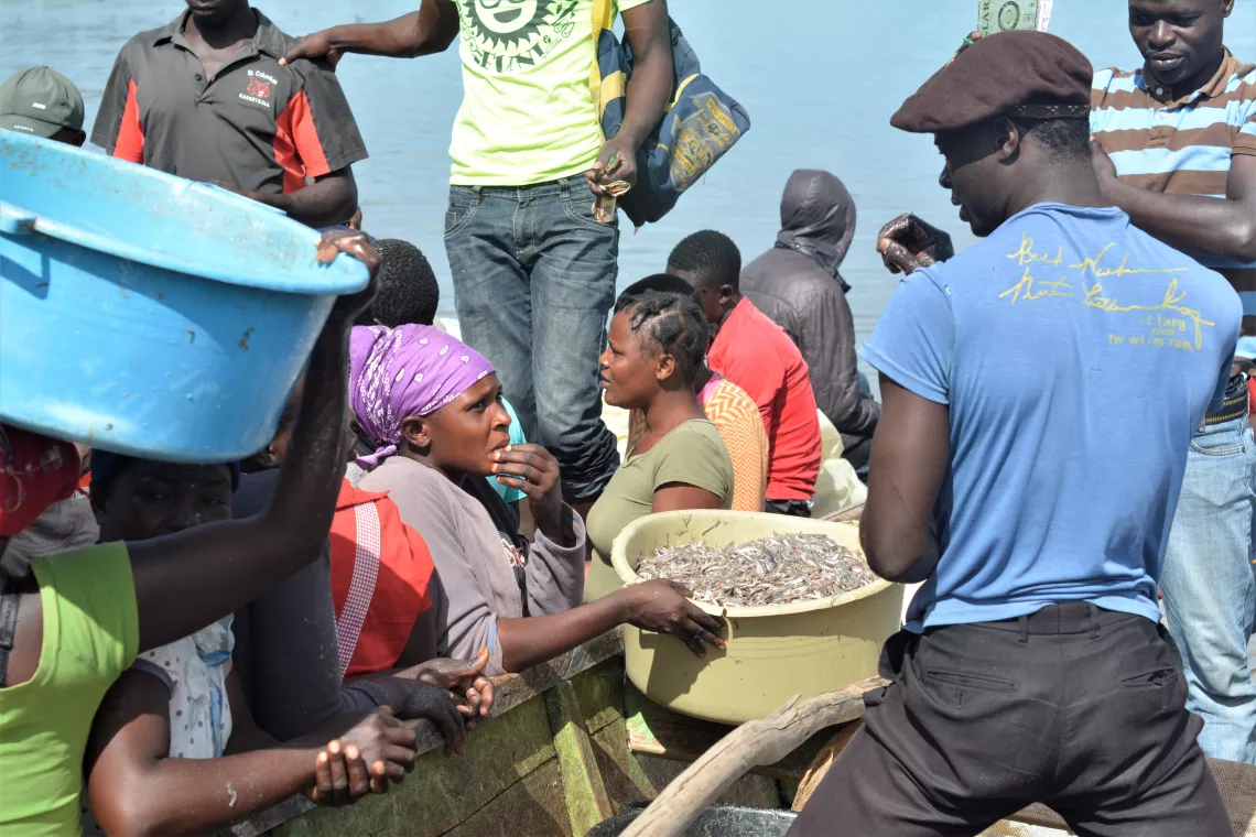 A fisherman talks to a woman buying fish, while his colleague collects money behind her (photo taken before COVID-19)