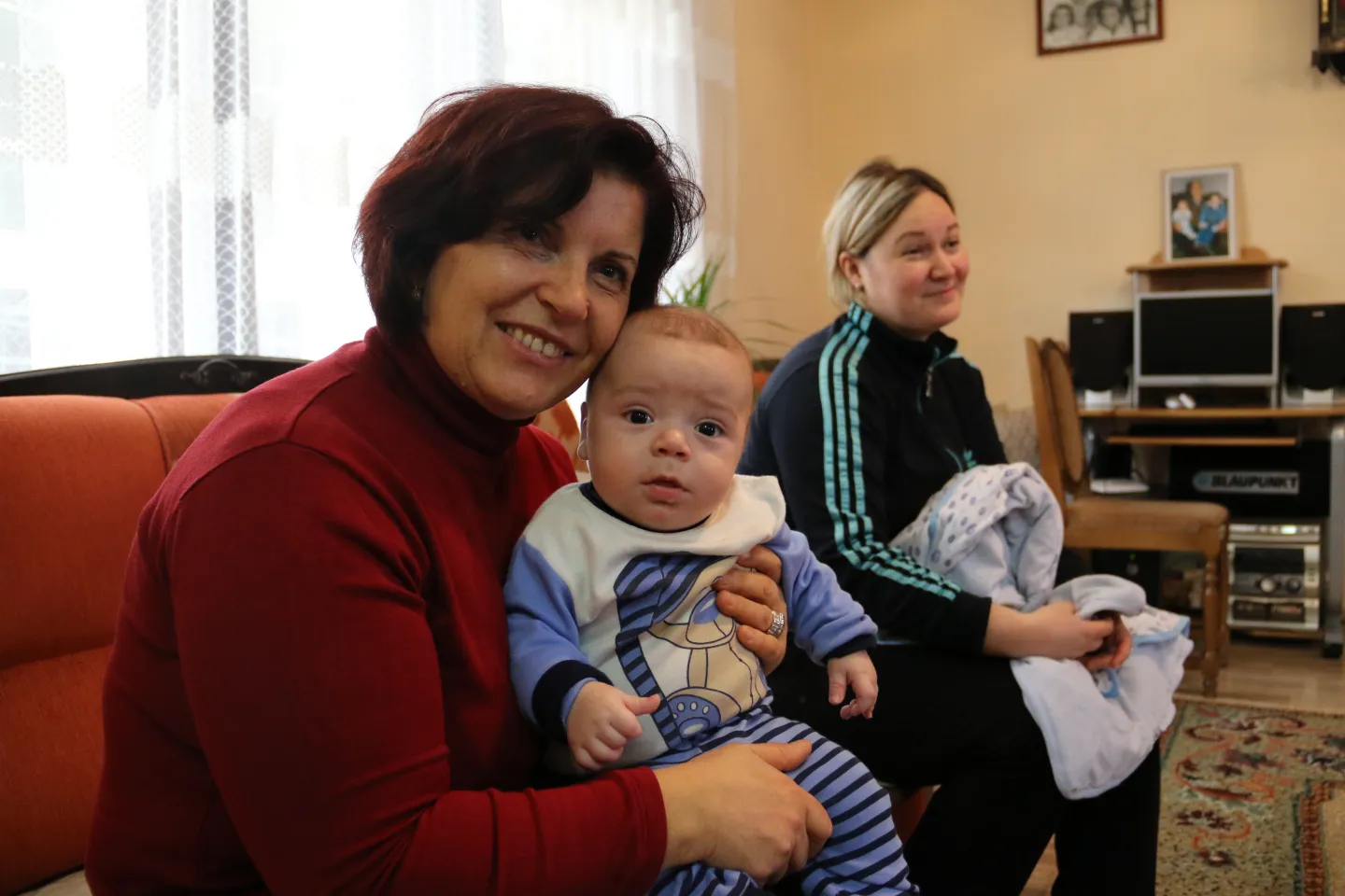 Nurse Neime holding Gylxhan's newborn during a home visit.
