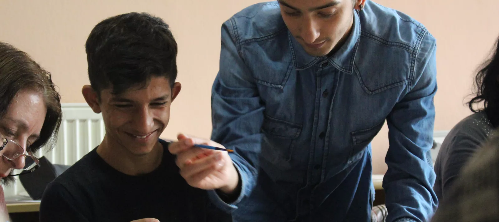 Sejnur Veshall assisting a young boy with his decorative plate at a Golden Hands workshop.