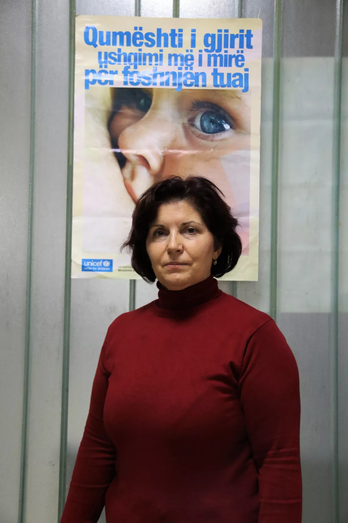 Nurse Neime in the Main Family Health Center standing next to a sign reading &ldquo;Breastmilk is the best nutrition for your baby&rdquo;.