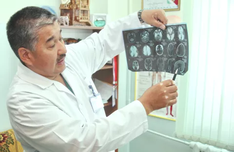 A male doctor in lab coat holds up a scan to the light
