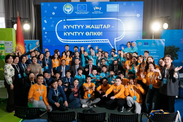 A group of people posing for a camera, on the background there is a digital banner with the project's title and logos