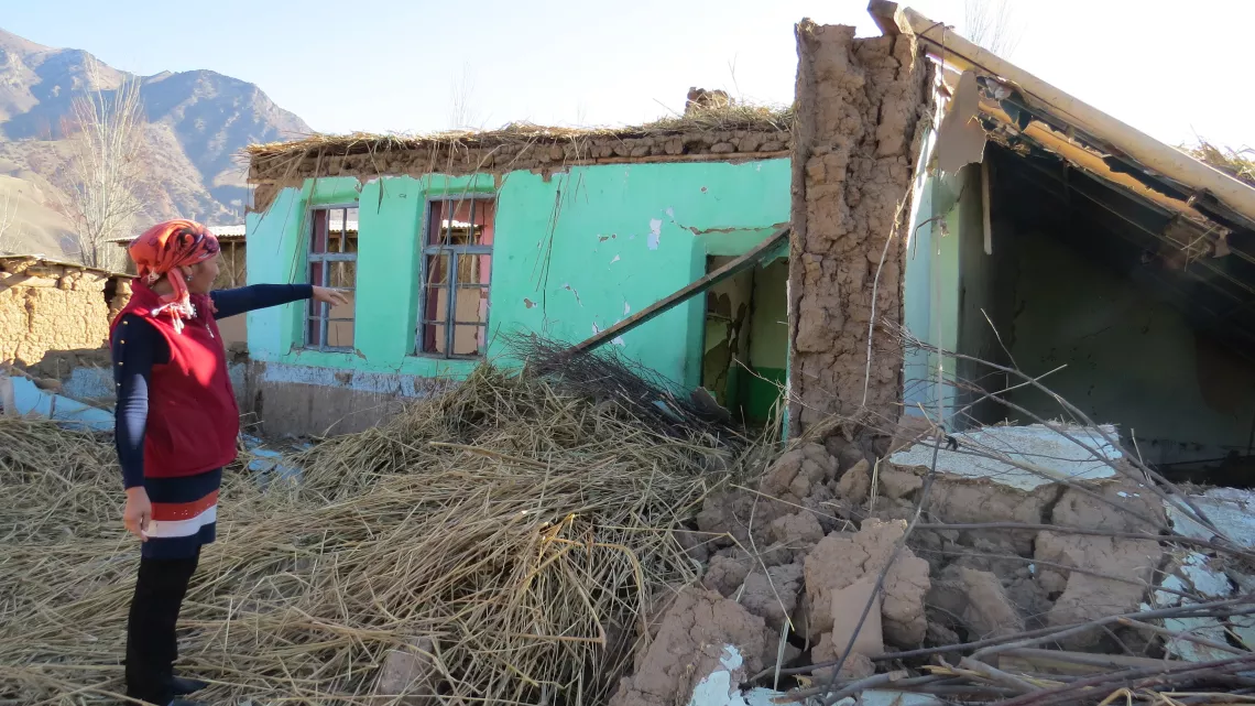 A woman shows her house, destroyed  as a result of earthquake
