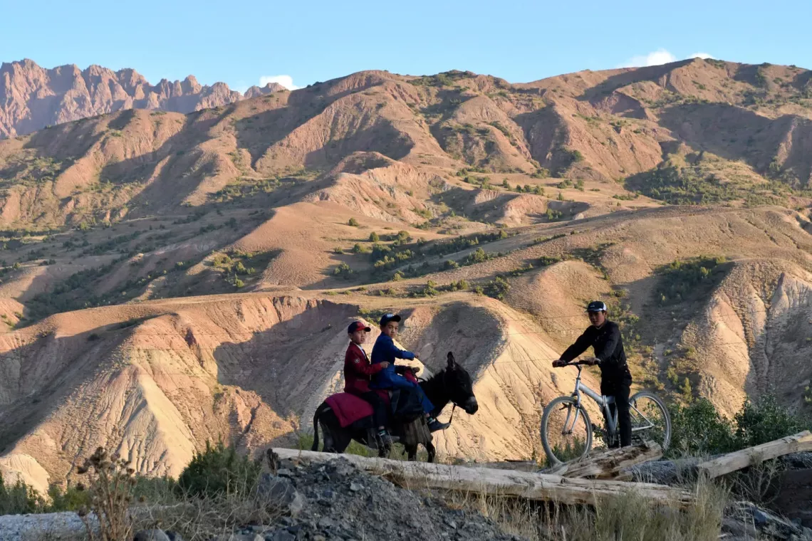 boys on a horse and a bike riding through a mountain area