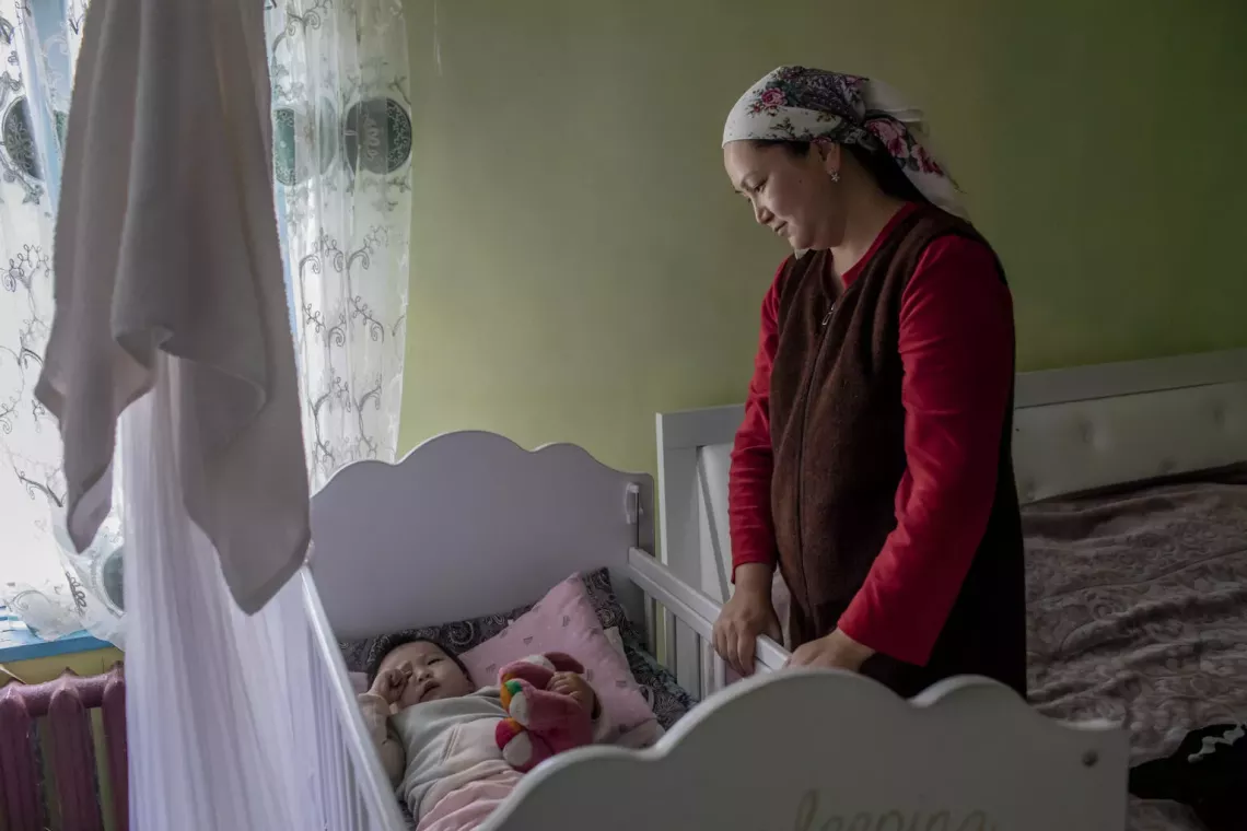 a mother standing next to her baby in a crib