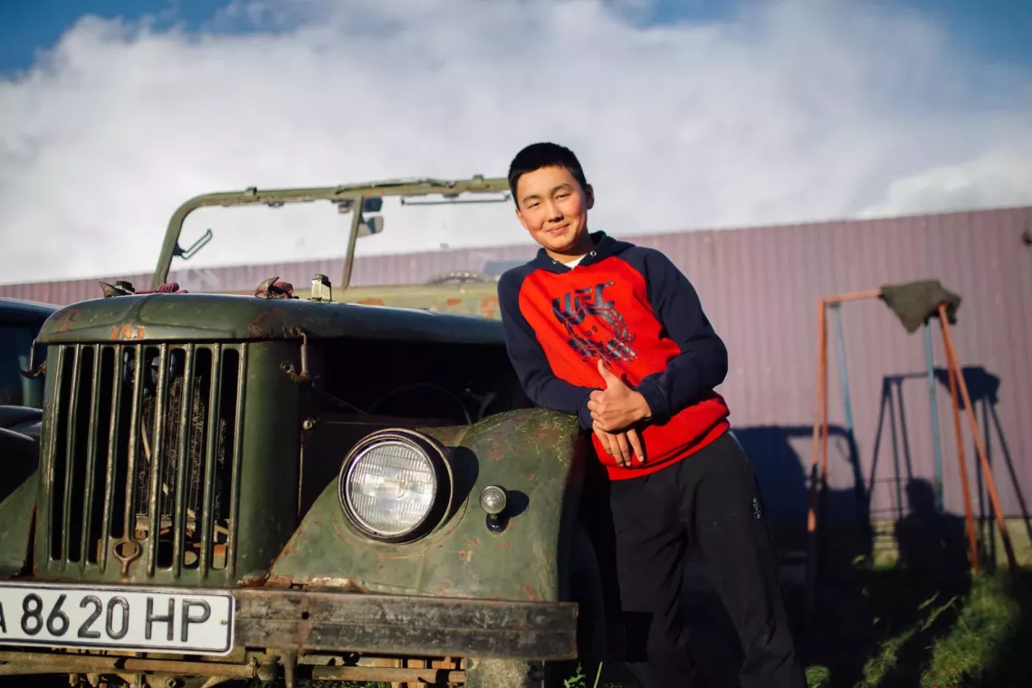 a teenage boy is next to an old car