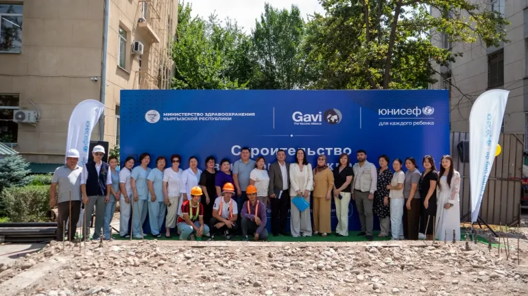 A group photo with a huge banner from the event with all participants on the site of the warehouse construction