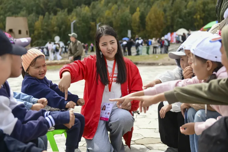 A UNICEF volunteer is playing national Kyrgyz game with children in Kyrchyn