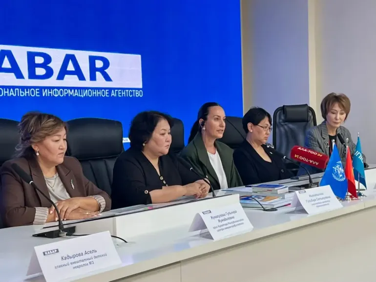 A photo from the press conference with speakers sitting on the table
