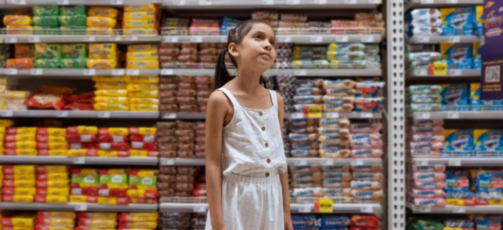 Una ni&ntilde;a mira hacia los estantes dentro de un pasillo de supermercado