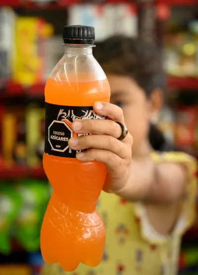 Una ni&ntilde;a sostiene una botella de soda que se muestra en primer plano
