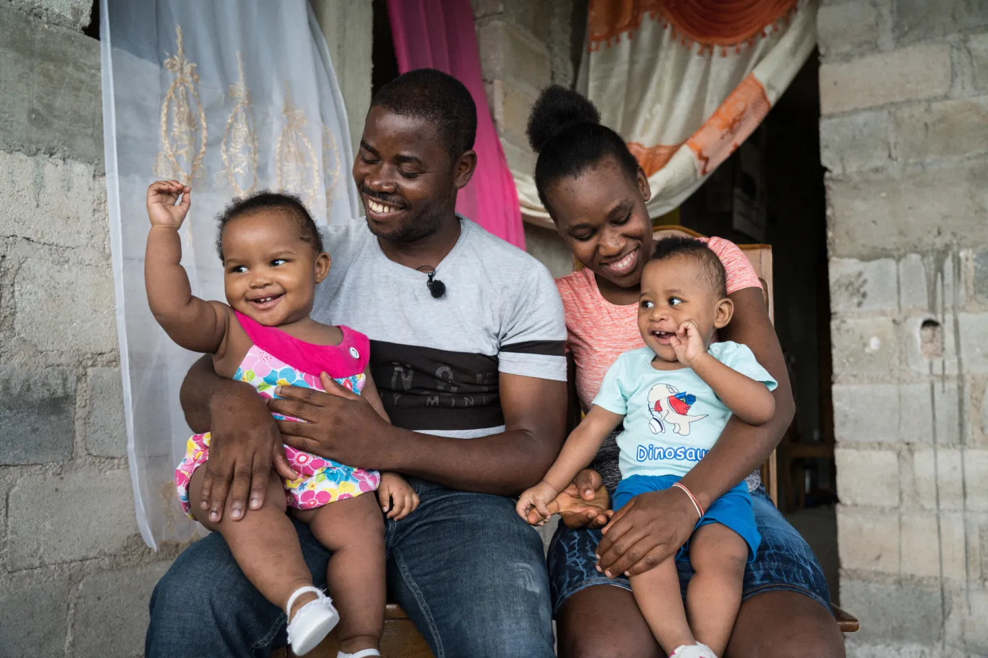 Mother, father and two little kids smiling.