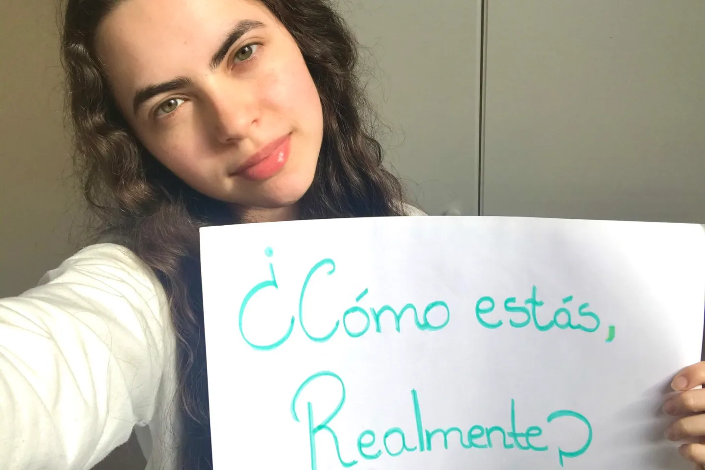 Una joven muestra un cartel que dice: &iquest;C&oacute;mo est&aacute;s, realmente?