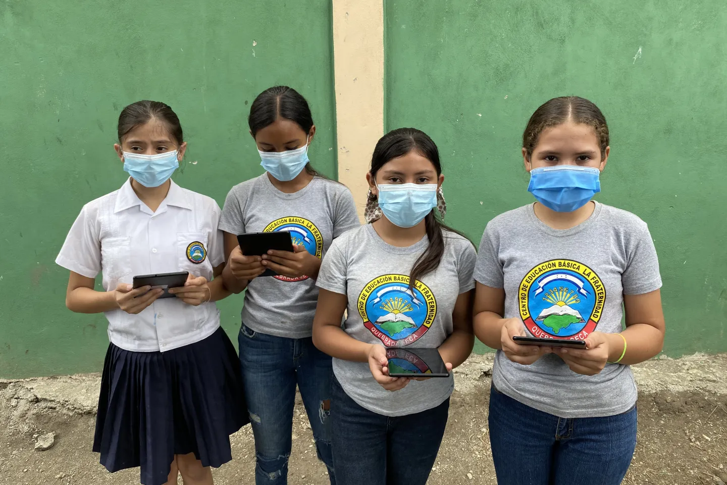 Group of girls wearing masks and holding tablets