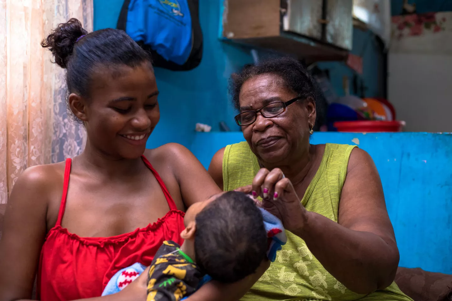 Mother, 19, holds her 18-month-old son, who has cerebral palsy, as she sits next to her grandmother in Belize