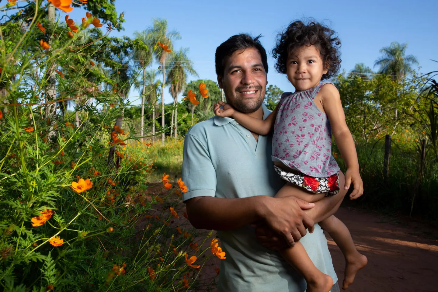 Rafael Alfonso Araujo, 27, holds his daughter Selva, 2, outside of their home in Paraguay
