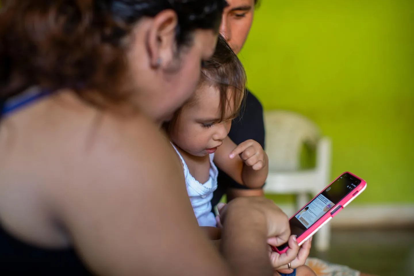 Heisell Tellez, 27, (left) and Hosten Alem&aacute;n, 26, (right) watch videos of the therapies with their daughter Rouss Alem&aacute;n (center), who -- after the therapies -- has managed to walk and perform daily activities, in their home in Jinotepe, Nicaragua on September 6th, 2020.