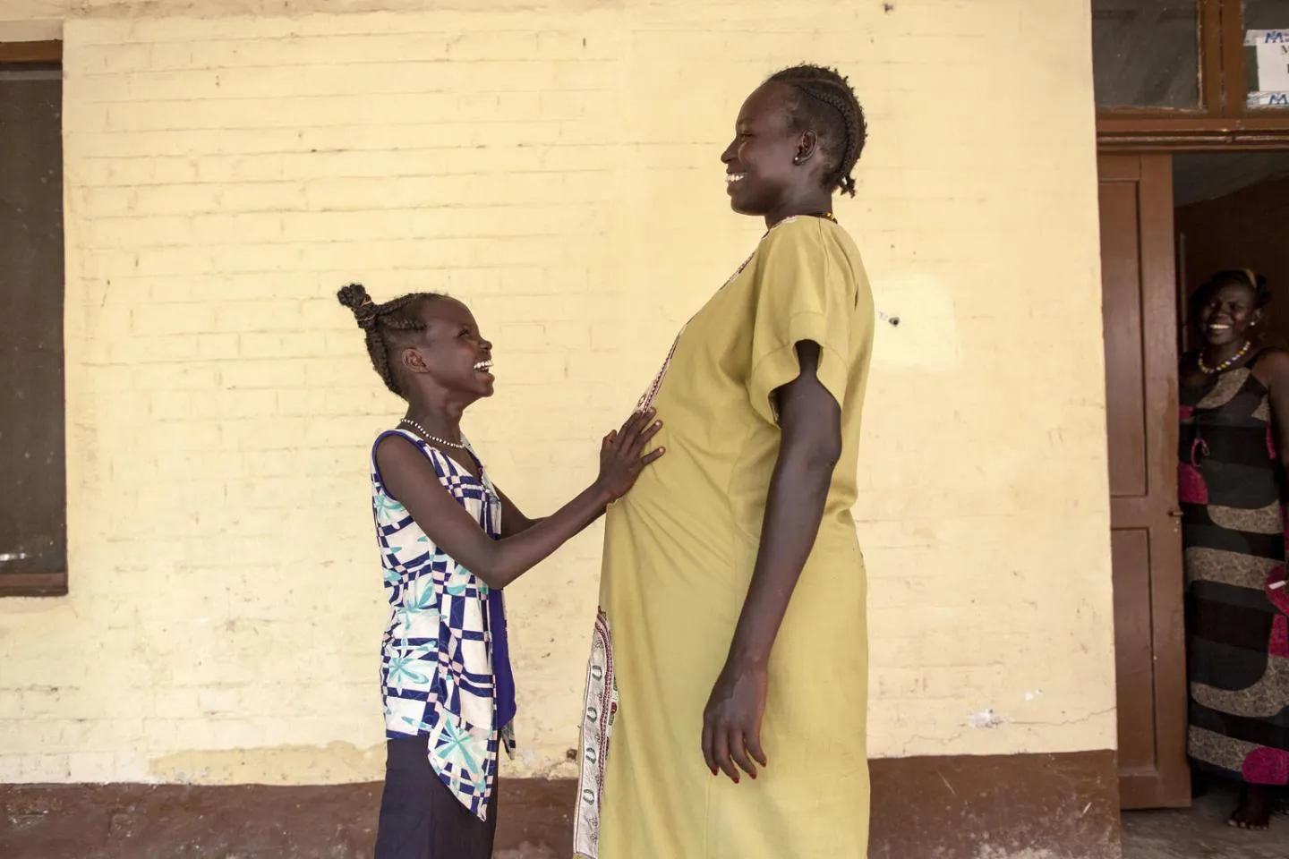 11 year old Nyanyiik Abile touches the stomach of Sundoay John - who is 9 months pregnant with her second child - outside the UNICEF-supported maternity ward at Malakal Teaching Hospital, South Sudan.