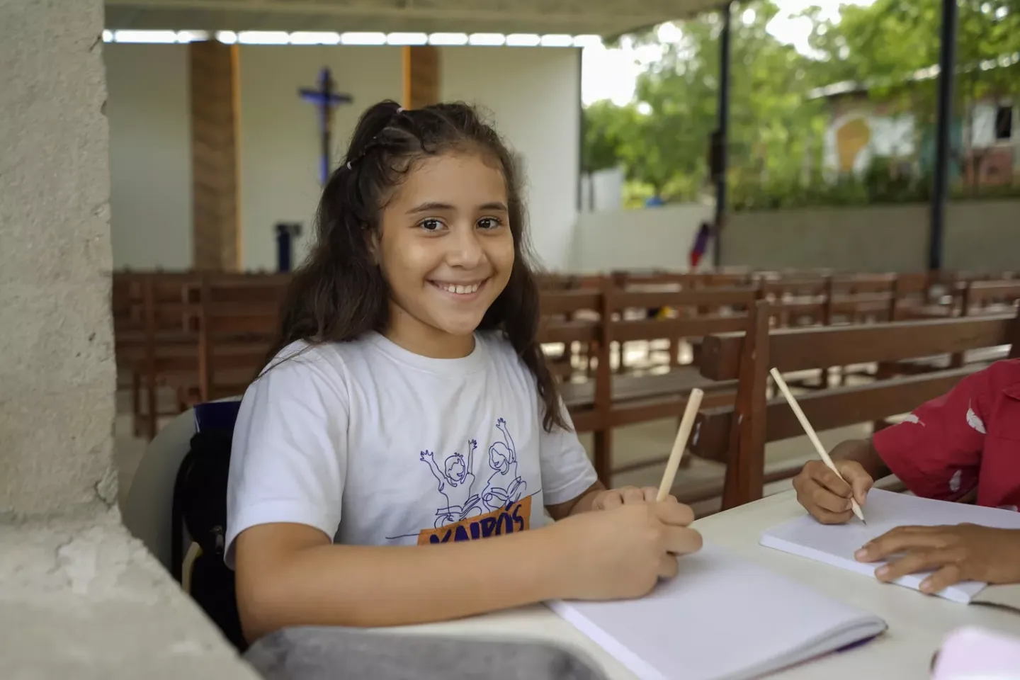 Una ni&ntilde;a sonriendo mientras sostiene un l&aacute;piz